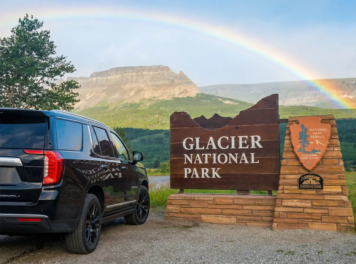 GMC Yukon Denali Parked By Glacier National Park Entrance Sign